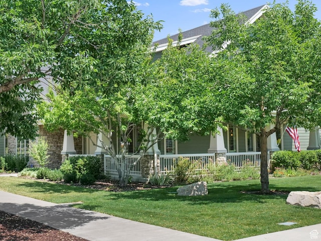 10693 S Vermillion Dr, South Jordan, UT 84009 - obstructed view of property featuring covered porch, stone siding, and a front yard