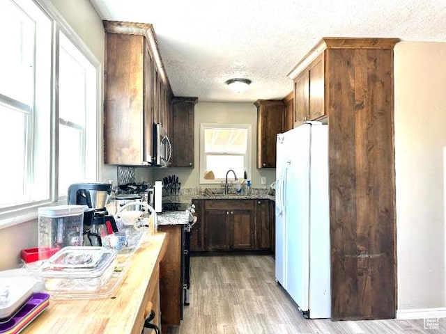 3060 S 2500 E, Vernal, UT 84078 - kitchen featuring freestanding refrigerator, stainless steel microwave, a textured ceiling, light wood finished floors, and dark brown cabinetry