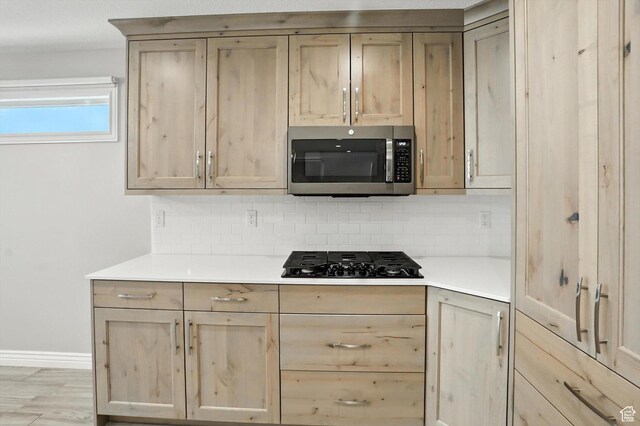 1470 N Cobblewood Ct, Kaysville, UT 84037 - kitchen featuring stainless steel microwave, black gas cooktop, light brown cabinets, and tasteful backsplash