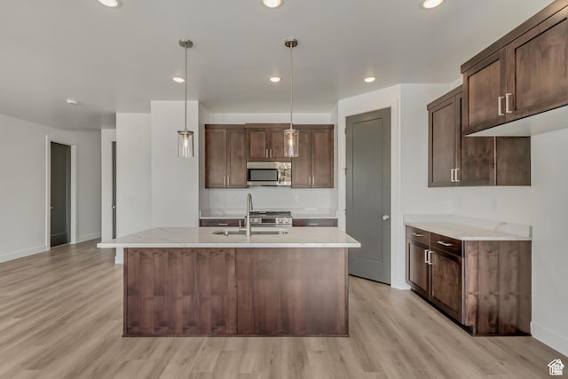 1352 N 1440 E Unit 21, Payson, UT 84651 - kitchen with stainless steel microwave, light wood-style flooring, pendant lighting, a kitchen island with sink, and dark brown cabinetry