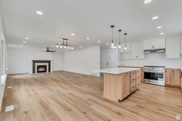 13749 S Crimson Patch Way, Riverton, UT 84096 - kitchen with high end range, under cabinet range hood, recessed lighting, light countertops, and a glass covered fireplace