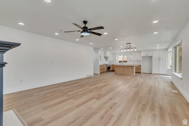 13749 S Crimson Patch Way, Riverton, UT 84096 - unfurnished living room featuring recessed lighting, light wood-style flooring, ceiling fan, and a chandelier