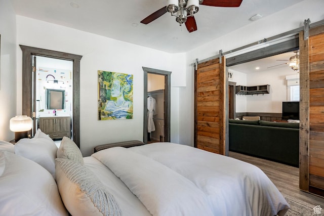 416 Marsac Ave, Park City, UT 84060 - bedroom featuring a barn door, wood finished floors, ceiling fan, a walk in closet, and connected bathroom