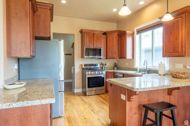 1959 W Golden Pond Way S, Orem, UT 84059 - kitchen with stainless steel appliances, a peninsula, a kitchen breakfast bar, brown cabinetry, and light wood-type flooring