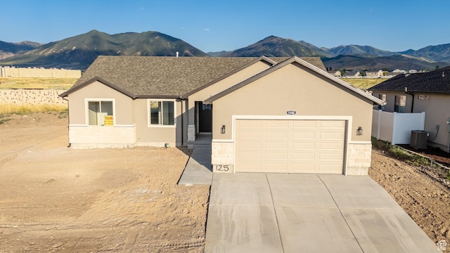 1182 N Berra Blvd, Tooele, UT 84074 - ranch-style house featuring a mountain view, concrete driveway, an attached garage, and stone siding