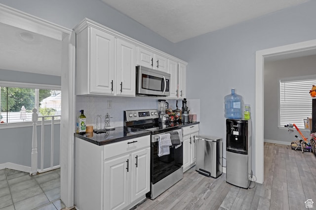 2217 Monroe Blvd, Ogden, UT 84401 - kitchen featuring appliances with stainless steel finishes, dark countertops, white cabinetry, decorative backsplash, and light wood-style floors