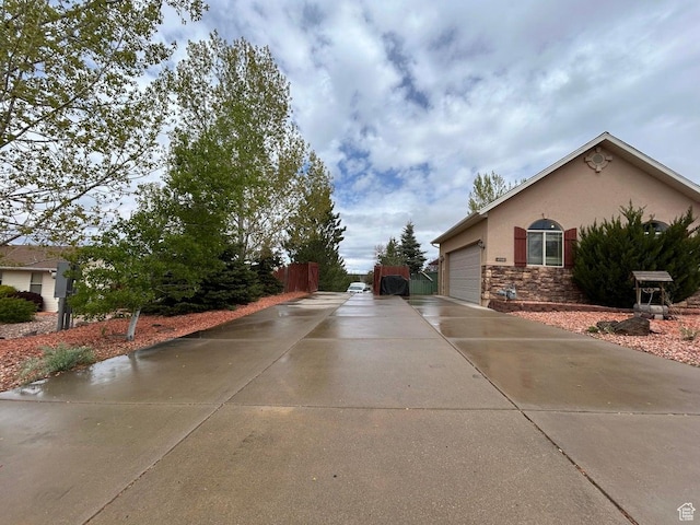 4140 W 975 S, Cedar City, UT 84720 - view of side of property featuring stone siding, stucco siding, an attached garage, and driveway