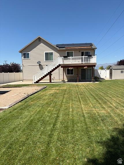 1579 W 2050 N, Clinton, UT 84015 - back of property with stairs, roof mounted solar panels, a wooden deck, a fenced backyard, and a patio area