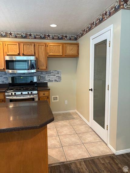 1579 W 2050 N, Clinton, UT 84015 - kitchen with appliances with stainless steel finishes, dark countertops, brown cabinets, and backsplash