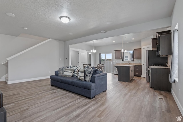 8687 N Oakmont Aly, Eagle Mountain, UT 84005 - living room with light wood finished floors, stairway, a chandelier, and a textured ceiling