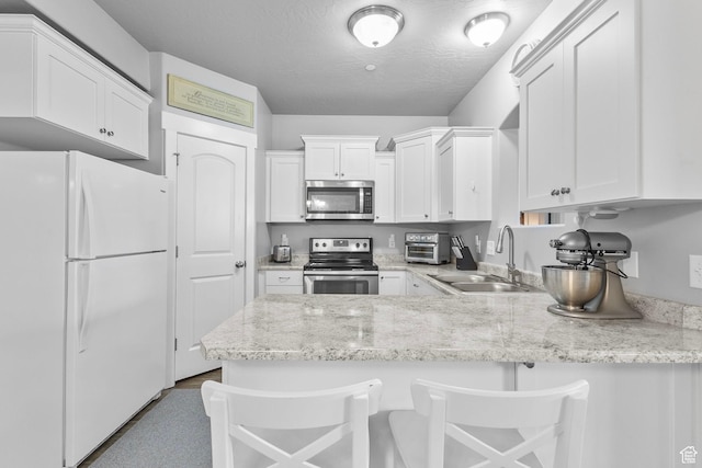217 W Ridge Rd, Saratoga Springs, UT 84045 - kitchen with stainless steel appliances, a peninsula, white cabinetry, light stone counters, and a breakfast bar area