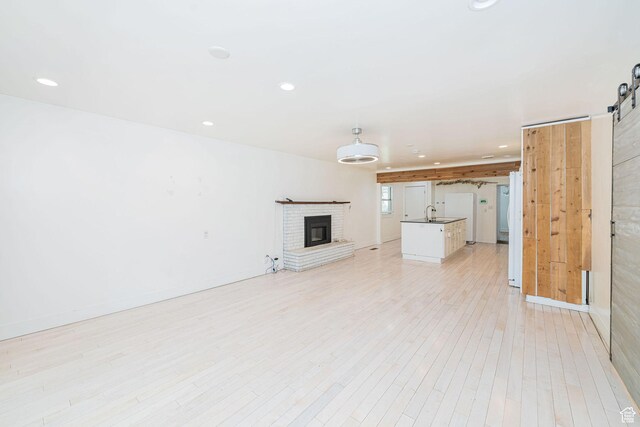 460 S 1074 E, Provo, UT 84606 - unfurnished living room with a barn door, light wood finished floors, recessed lighting, and a fireplace