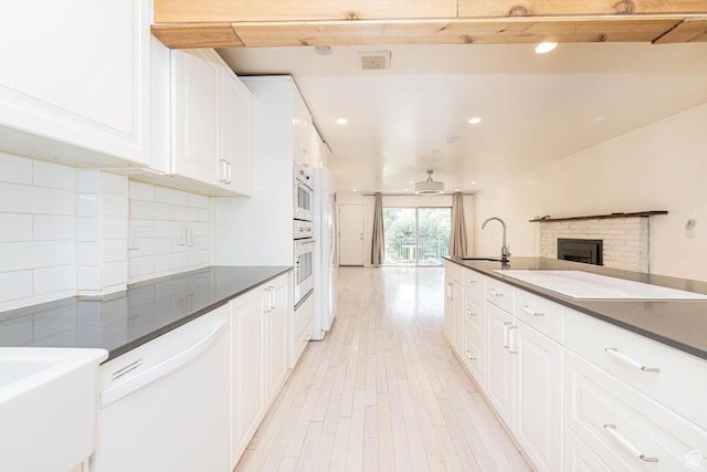 460 S 1074 E, Provo, UT 84606 - kitchen with white appliances, dark countertops, a brick fireplace, light wood finished floors, and white cabinets