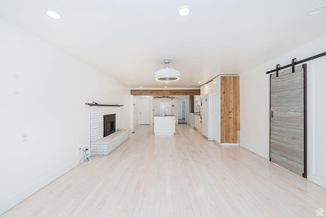 460 S 1074 E, Provo, UT 84606 - unfurnished living room featuring a barn door, recessed lighting, a fireplace, and light wood-style flooring