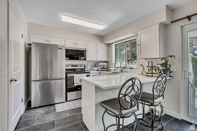 857 E 575 N, Layton, UT 84041 - kitchen featuring stainless steel appliances, a peninsula, light countertops, tasteful backsplash, and white cabinets