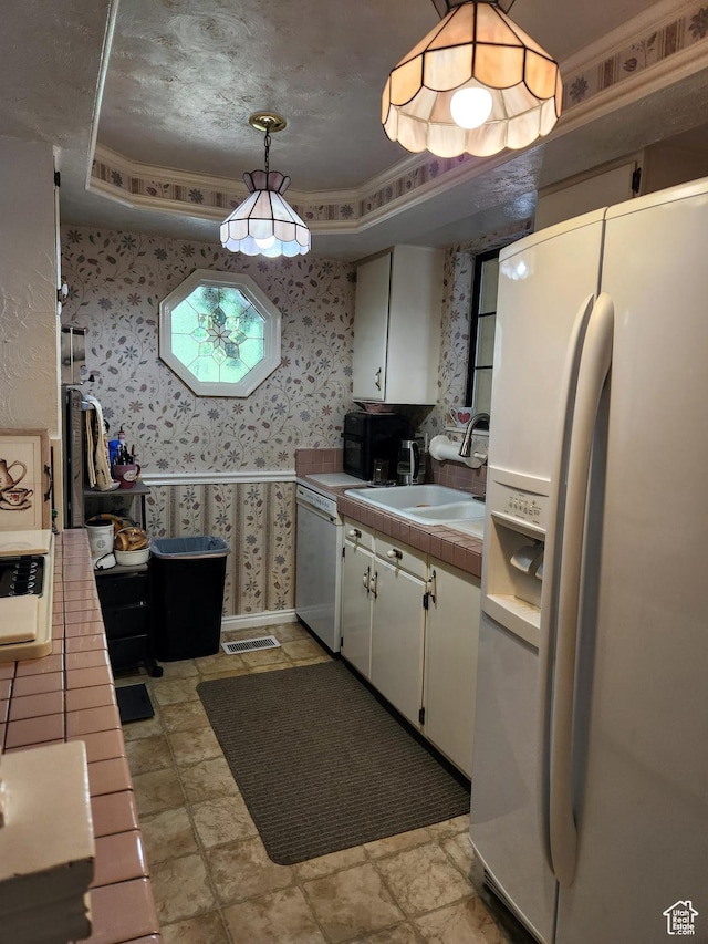 8857 S Capella Way E, Sandy, UT 84093 - kitchen with white appliances, a raised ceiling, wallpapered walls, tile counters, and white cabinets