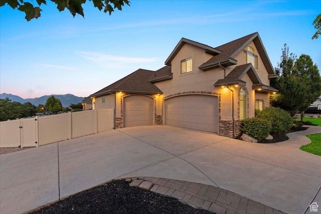 12469 S Patriot Hill Way, Herriman, UT 84096 - view of front of home featuring concrete driveway, an attached garage, stone siding, and a gate
