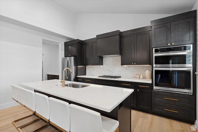 12469 S Patriot Hill Way, Herriman, UT 84096 - kitchen featuring stainless steel appliances, lofted ceiling, light wood-style flooring, decorative backsplash, and a kitchen bar