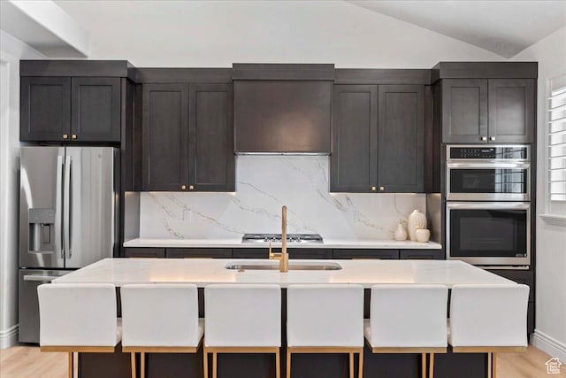 12469 S Patriot Hill Way, Herriman, UT 84096 - kitchen with stainless steel appliances, backsplash, light countertops, lofted ceiling, and light wood-type flooring
