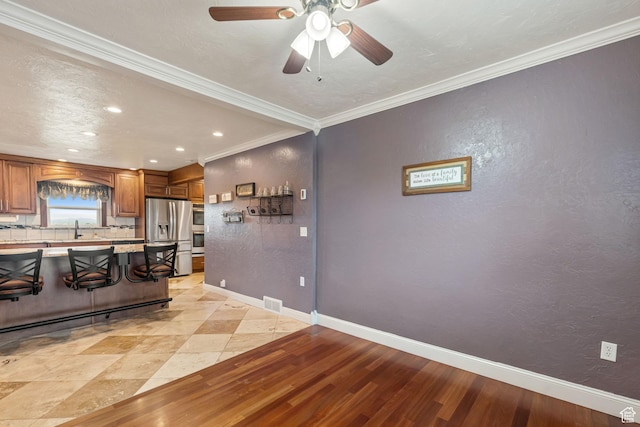 2214 S 1600 E, Preston, ID 83263 - kitchen featuring stainless steel appliances, a kitchen breakfast bar, brown cabinetry, light countertops, and a ceiling fan