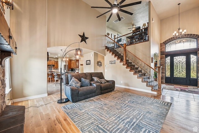 3195 N 1350 W, Pleasant View, UT 84414 - living room featuring a towering ceiling, a chandelier, arched walkways, stairs, and light wood-type flooring