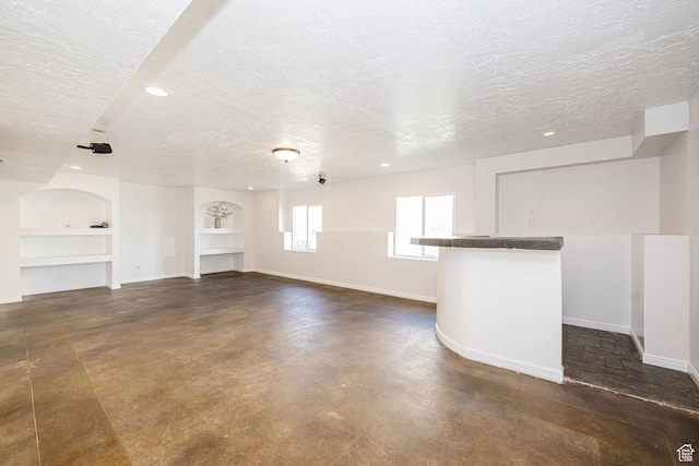 383 E Manti Dr S, Draper, UT 84020 - unfurnished living room featuring a textured ceiling, built in shelves, concrete floors, and recessed lighting