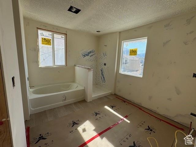 432 W Sapphire Dr Unit 7012, Tooele, UT 84074 - full bath featuring a textured ceiling, a garden tub, plenty of natural light, and wood finished floors
