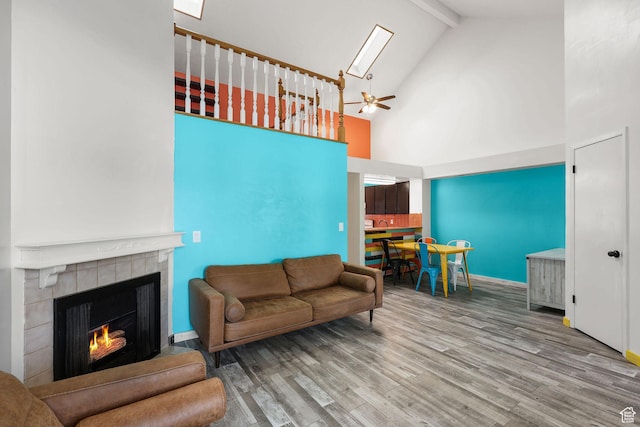 1428 W Beacon Hill Cir S Unit 1428, Salt Lake City, UT 84123 - living room featuring wood finished floors, a tiled fireplace, beamed ceiling, a ceiling fan, and high vaulted ceiling
