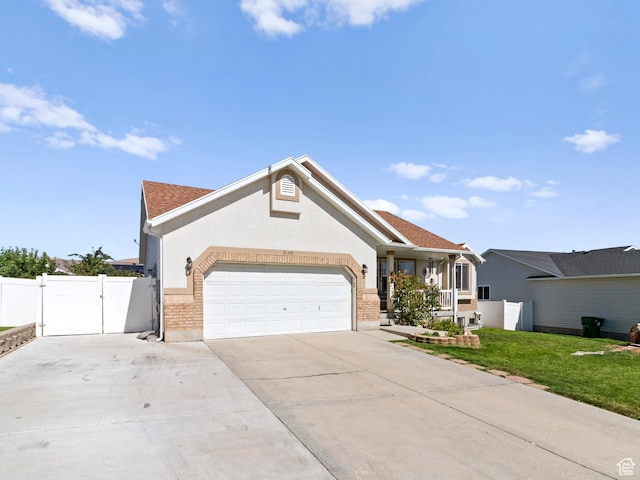 3646 S Elk Point Dr, Magna, UT 84044 - view of front of house featuring a gate, a garage, driveway, brick siding, and stucco siding