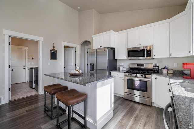 933 S 250 W, Vernal, UT 84078 - kitchen with stainless steel appliances, high vaulted ceiling, dark wood-style flooring, a breakfast bar area, and white cabinets