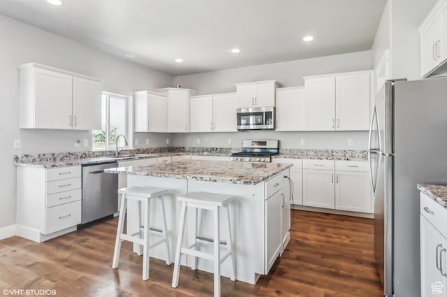 2086 W White Pine Dr S, Layton, UT 84041 - kitchen with appliances with stainless steel finishes, a kitchen island, white cabinets, a breakfast bar area, and recessed lighting
