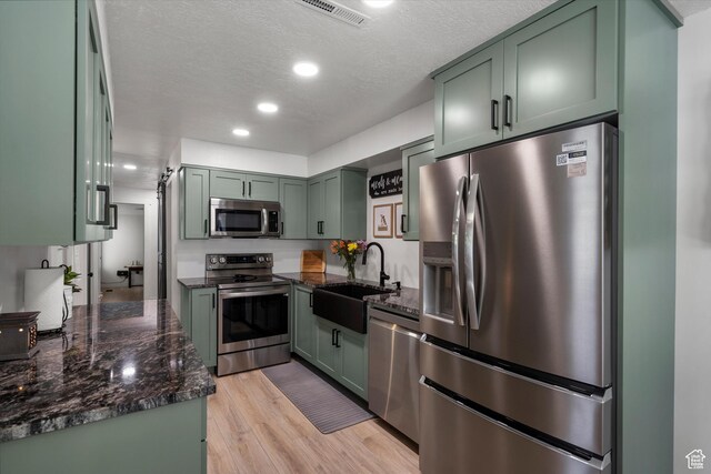 866 Brookside Ln, Centerville, UT 84014 - kitchen with appliances with stainless steel finishes, green cabinetry, dark stone countertops, light wood finished floors, and recessed lighting