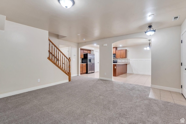 1158 W 150 S, Springville, UT 84663 - unfurnished living room with arched walkways, light tile patterned flooring, light colored carpet, and stairs