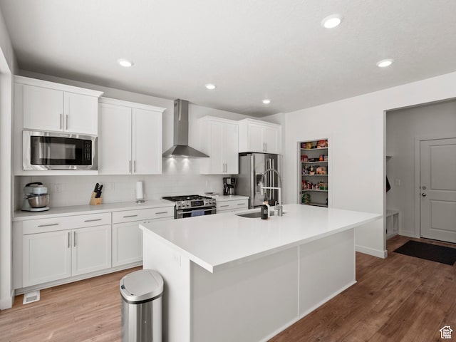 1583 W Andover Rd, South Jordan, UT 84095 - kitchen featuring wall chimney range hood, appliances with stainless steel finishes, an island with sink, tasteful backsplash, and white cabinets