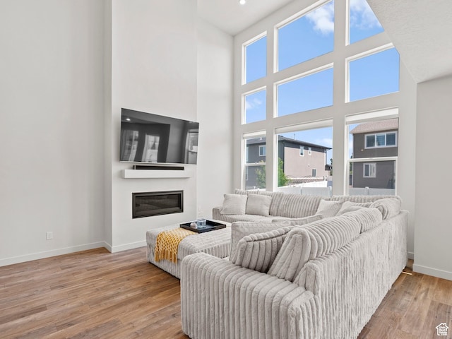 1583 W Andover Rd, South Jordan, UT 84095 - living room with healthy amount of natural light, wood finished floors, a glass covered fireplace, and a high ceiling