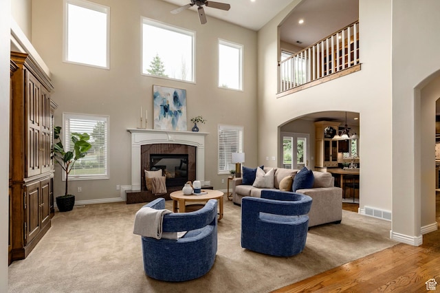 999 S Fairway Cir, Fruit Heights, UT 84037 - living room with a ceiling fan, arched walkways, a towering ceiling, a fireplace, and light colored carpet
