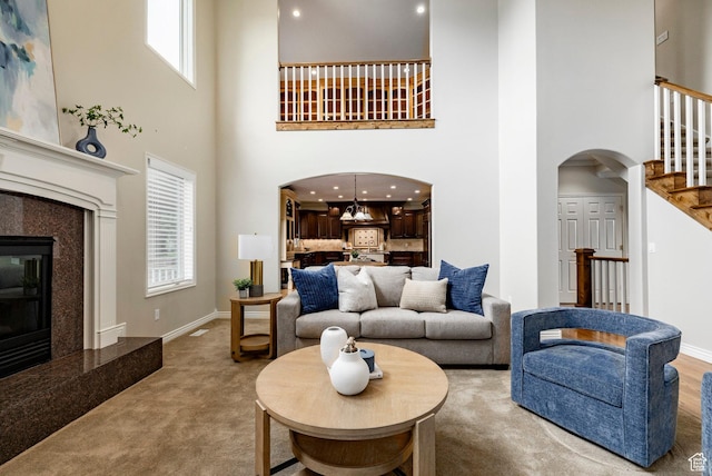 999 S Fairway Cir, Fruit Heights, UT 84037 - living room with arched walkways, a towering ceiling, stairway, a premium fireplace, and light carpet