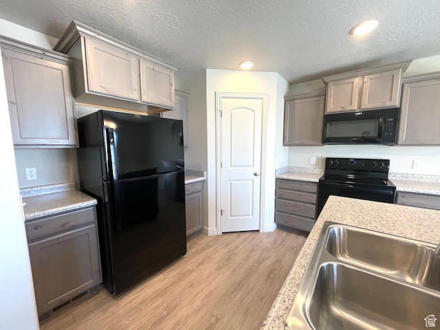 228 W 2370 N, Tooele, UT 84074 - kitchen with black appliances, gray cabinets, a textured ceiling, light wood-style floors, and light countertops