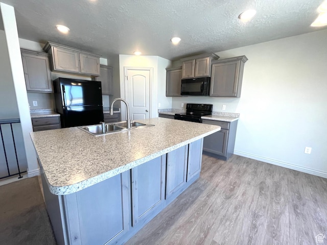 228 W 2370 N, Tooele, UT 84074 - kitchen with black appliances, gray cabinets, light wood-style flooring, a textured ceiling, and an island with sink