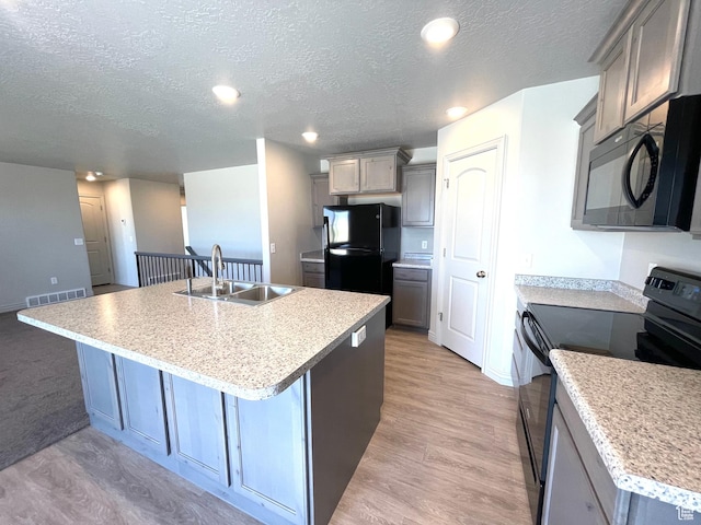 228 W 2370 N, Tooele, UT 84074 - kitchen with black appliances, a textured ceiling, a kitchen island with sink, gray cabinetry, and light countertops