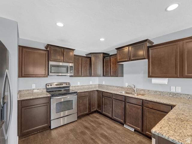 81 E E Side Hill Ln S, Draper, UT 84020 - kitchen with appliances with stainless steel finishes, dark wood-style flooring, dark brown cabinets, recessed lighting, and light stone countertops