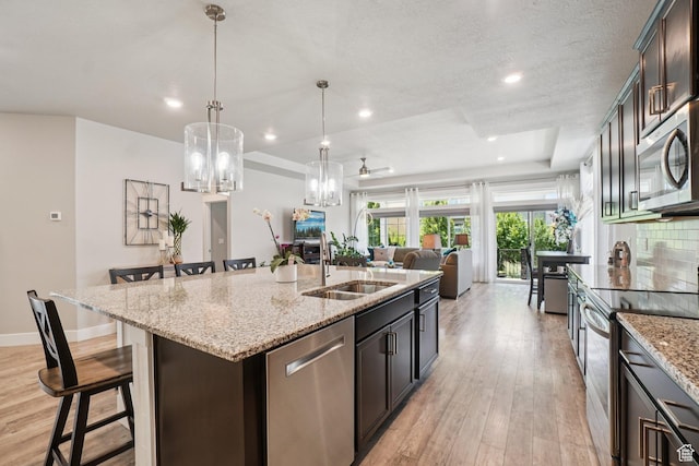 287 S Hayes Well Ln, Saratoga Springs, UT 84045 - kitchen with appliances with stainless steel finishes, a raised ceiling, a chandelier, a kitchen island with sink, and a breakfast bar