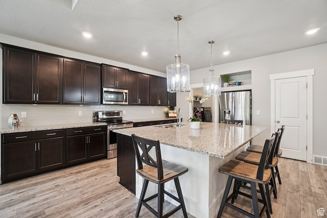 287 S Hayes Well Ln, Saratoga Springs, UT 84045 - kitchen with appliances with stainless steel finishes, light wood-style flooring, a chandelier, a kitchen bar, and backsplash