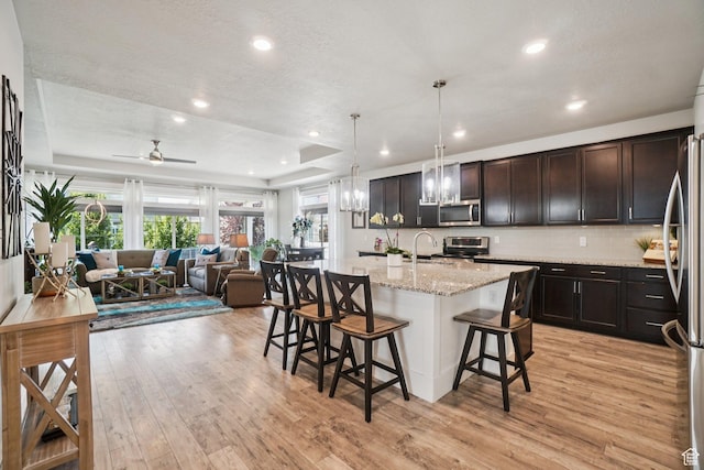287 S Hayes Well Ln, Saratoga Springs, UT 84045 - kitchen featuring appliances with stainless steel finishes, a raised ceiling, a kitchen bar, light wood-type flooring, and recessed lighting