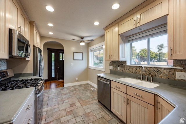 3076 S Melbourne St, Millcreek, UT 84106 - kitchen with stainless steel appliances, light brown cabinetry, arched walkways, tasteful backsplash, and recessed lighting