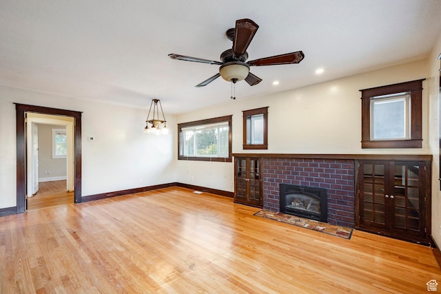 3076 S Melbourne St, Millcreek, UT 84106 - unfurnished living room with a brick fireplace, light wood-style flooring, ceiling fan, recessed lighting, and a chandelier