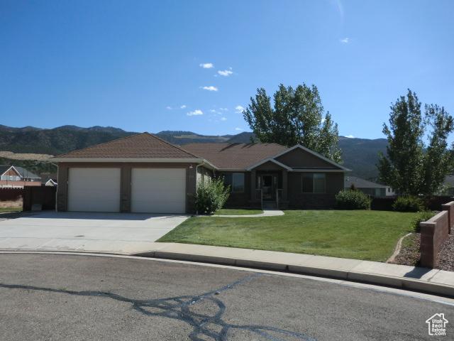 320 S 1125 W, Parowan, UT 84761 - ranch-style home featuring a garage, a mountain view, concrete driveway, and a front lawn