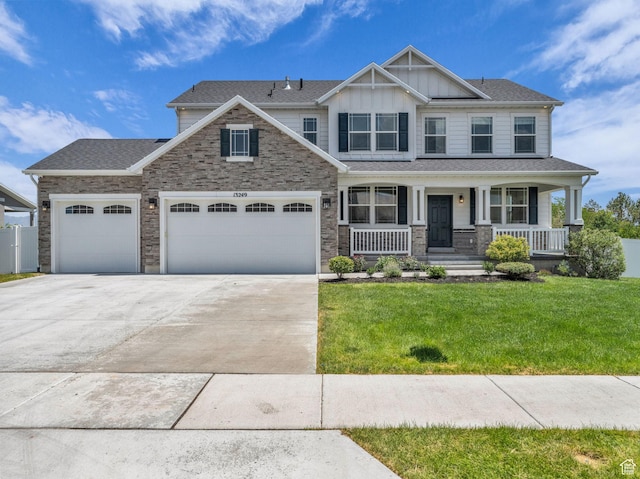 13249 S Shearing Cv, Herriman, UT 84096 - craftsman-style home with concrete driveway, board and batten siding, an attached garage, a front lawn, and covered porch