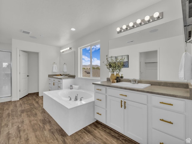 13249 S Shearing Cv, Herriman, UT 84096 - bathroom featuring two vanities, a garden tub, wood finished floors, an enclosed shower, and recessed lighting