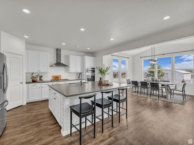 13249 S Shearing Cv, Herriman, UT 84096 - kitchen featuring wall chimney range hood, dark countertops, stainless steel appliances, dark wood finished floors, and recessed lighting